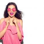 Image of a smiling woman with two love heart shaped lolly pops over her eyes