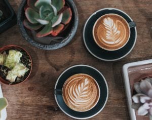 Image of two coffees and a plant
